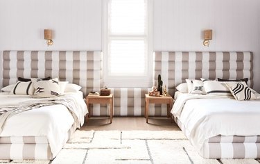 Bedroom with taupe patterned headboards, bedding, nightstands, sconces.