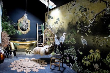 Room with tub, colorful wallpaper with cranes, and swinging chair