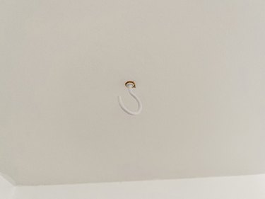 Install a cup hook in the ceiling using a drywall anchor, if needed.