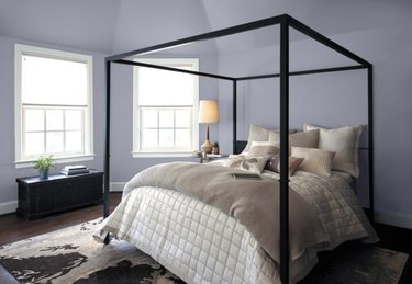 Bedroom with taupe bedding and lavender walls.