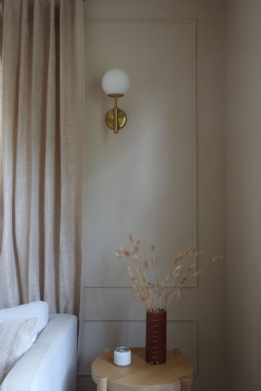 a globe sconce hangs on a taupe wall with wall moldings