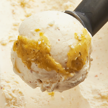 Charred Corn Curd, Cotija, and Tajin on a scoop. The ice creme is beige and features ribbons of yellow corn curd.