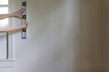 Drawing the placement of the wall molding boxes on the wall with a pencil and level