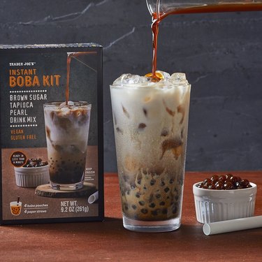 Trader Joe's Instant Boba Kit showing the box, a glass of iced tea with milk, and tapioca pearls in a small white bowl