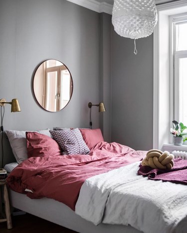 Gray bedroom with a mirror over bed and red bedding