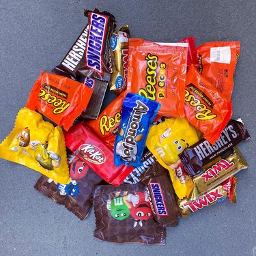 Pile of candy including Hershey's chocolate bars, M + M's, Almond Joy, Snickers, Twix, and Reeses.