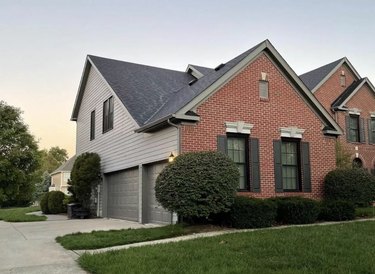 Gray siding on one wall and garage with red brick on the others