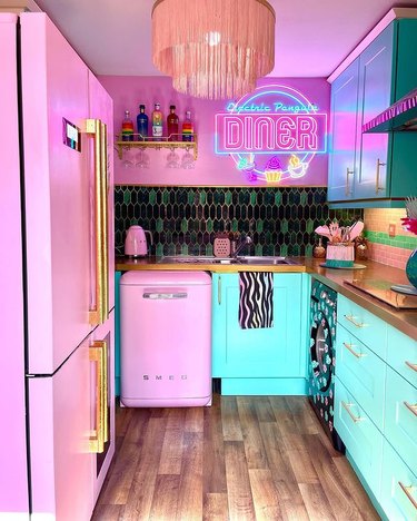 Colorful kitchen with pink and green appliances and a neon sign