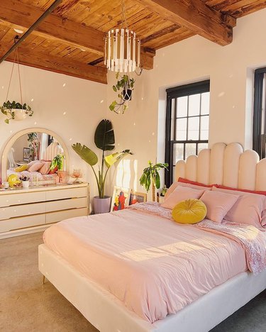 Bedroom with pink bed, scallop headboard, and plants
