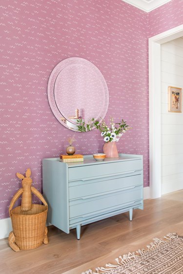 bedroom with pink wallpaper and light blue dresser