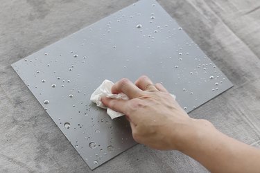 Blotting droplets of vinegar from painted glass with paper towel