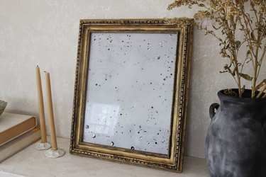 DIY antique gold mirror on shelf with dried flowers and beeswax candles