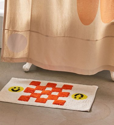 shower curtain with flower near bath mat with checkers and smiley faces