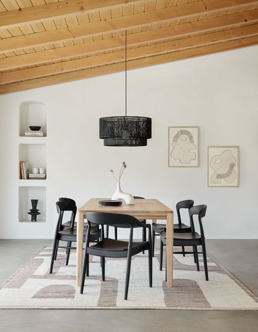 neutral dining room with black chairs over geometric rug