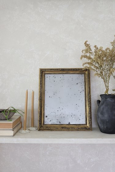 DIY antique gold mirror on shelf with dried flowers and beeswax candles