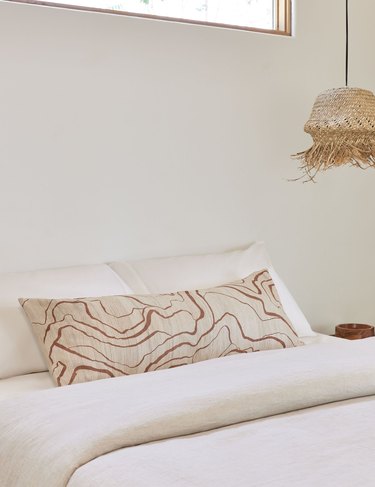 long lumbar pillow with wavy lines on white bed