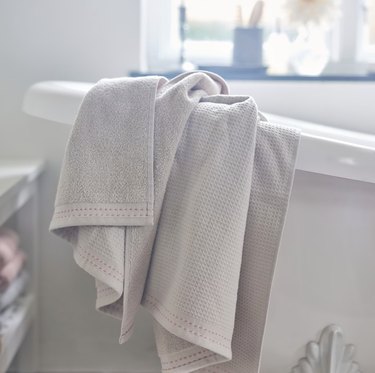 A beige bath towel hanging over a rack in the bathroom