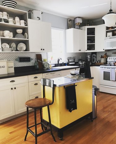 Black and white farmhouse kitchen with yellow vintage island