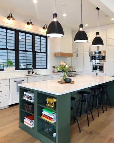 Black, white, and deep green kitchen with green island