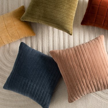 different colored velvet pillows on bed