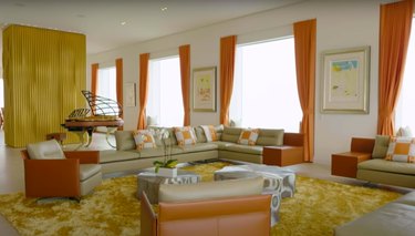 screenshot of a living room space with orange curtains and couches