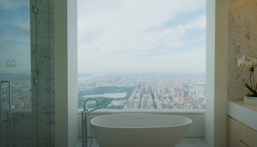 bathtub near large glass window with view of Manhattan
