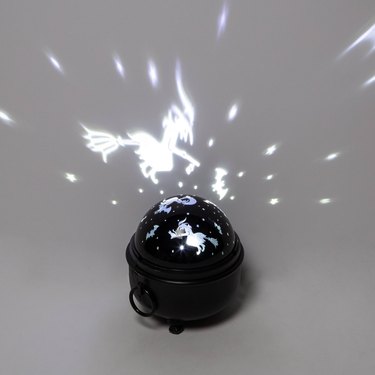 A black rotating light box that reflects flying witches and stars on the wall.