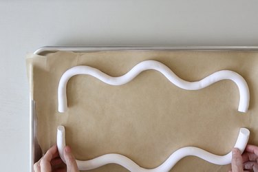 Placing two wavy log shapes onto parchment-lined baking tray