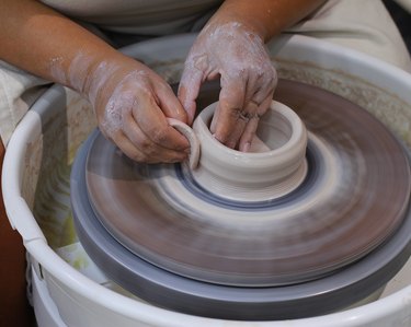 Hands spinning clay on a wheel to make pottery