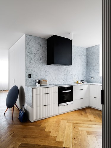 modern kitchen with white reeded cabinets and black hood