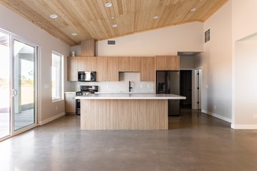 Minimalist Kitchen with a sloped wood ceiling, wood cabinets, and gray flooring