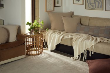 Living room with a beige couch with white throw and white rug