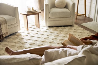 A living room with a white checkerboard and person reading on the couch