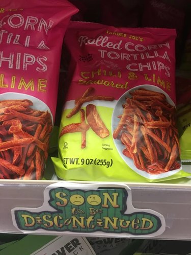 Trader Joe’s Chili and Lime Flavored Rolled Corn Tortilla Chips on the shelf with a sign that reads "soon to be discontinued"