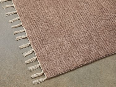 Corner of a pink rug with white fringe