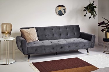 tufted velvet gray sofa with gold-accented splayed metal legs