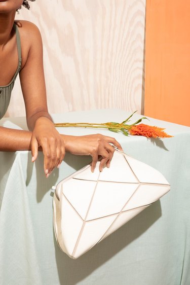 woman holding white clutch