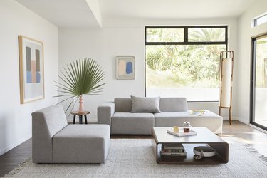 living room space with glass windows and light-colored sectional sofa with coffee table nearby