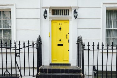 yellow door on white house with black fence