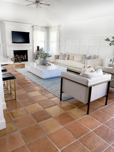 White living room with Saltillo tiles, cream sofas, and a gray carpet.