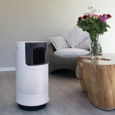 A white evaporative cooler in a living room with wood floors