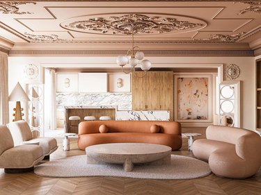Contemporary and traditional design elements converge in an open concept living room/kitchen with curved caramel and blush leather sofas and ornate molded ceilings.