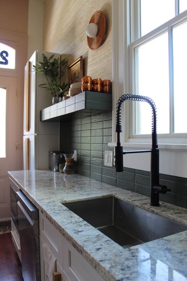 white granite countertop in kitchen with dark green tile backsplash