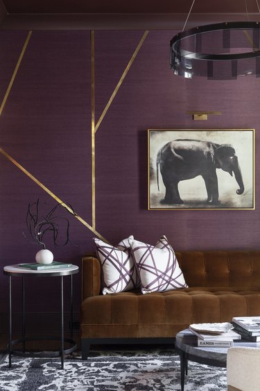 Purple walled living room with deep caramel velvet sofa and elephant art.