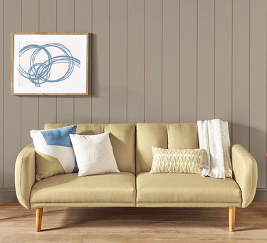 Light yellow couch with white pillows in front of a beige wall