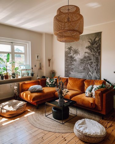 Boho living room with caramel velvet sofa, natural woven elements and plants.