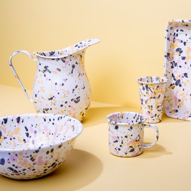 A white pitcher, mug, cup, bowl, and tray featuring purple, pink, and yellow splatters.