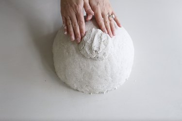 Pressing paper mache onto bottom of bowl to create footed base