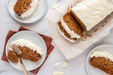 The pumpkin spice loaf being slide and put on white ceramic plates.