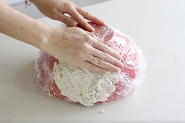 Pressing paper mache dough around the bowl